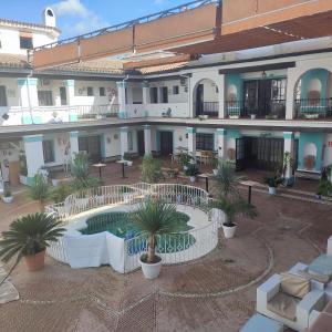 a large building with a courtyard with a pool and palm trees at Palacio Doñana , Rural & Luxury in El Rocío