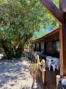 a wooden deck with white tables and chairs on it at Pousada & Camping Tubarão in Ilha do Mel