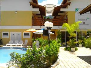 un hotel con piscina, sillas y sombrilla en Pousada Mosaico Brasil - Maresias, en Maresias