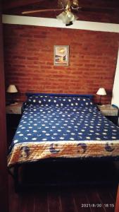 1 dormitorio con 1 cama con pared de madera en Cabañas Los Cerezos en Mina Clavero