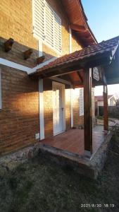 Casa de ladrillo con porche y puerta blanca en Cabañas Los Cerezos en Mina Clavero
