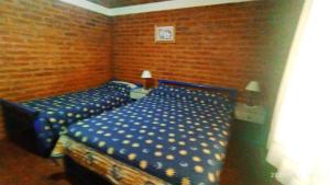 1 dormitorio con 2 camas y sábanas azules en Cabañas Los Cerezos en Mina Clavero