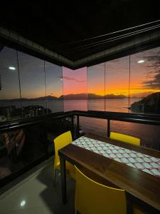 a table and chairs on a balcony with a sunset at Apartamento Porto Real Resort (11.1 402) com vista panorâmica in Angra dos Reis