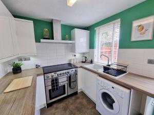 a kitchen with a stove and a washing machine at COMFORTABLE 4-Bed HOME WITH 3 BATHROOMS AND FREE PARKING! in Cambridge
