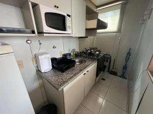 een kleine keuken met een wastafel en een magnetron bij Locking's Funcionários 4 in Belo Horizonte