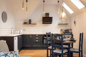 a kitchen with black cabinets and a table with chairs at Secluded Island Retreat - in the heart of the Anchorage in West Mersea