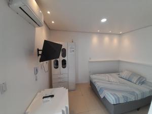 Habitación pequeña con cama y escritorio. en JK SUÍTE GARAGEM central en Pelotas