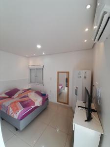 1 dormitorio con 1 cama y escritorio con ordenador en JK SUÍTE GARAGEM central en Pelotas
