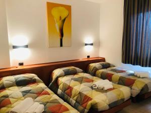a hotel room with two beds and a painting on the wall at Hotel Softwood in Recanati