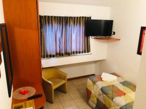 a room with a bed and a tv and a chair at Hotel Softwood in Recanati