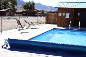 a swimming pool with two chairs and a building at Yellowstone Valley Inn in Wapiti
