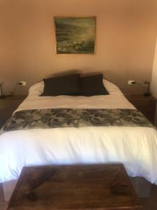 Un dormitorio con una cama blanca con una foto en la pared en Refugio Gaia en Chillán