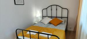 um pequeno quarto com uma cama com uma almofada laranja em Młynarska - słoneczne apartamenty em Piaseczno