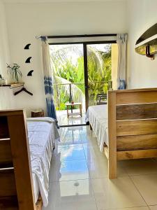 a bedroom with two beds and a large window at El Chante Surf House in Santa Teresa Beach