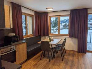 ein Wohnzimmer mit einem Tisch, Stühlen und Fenstern in der Unterkunft Am Römerweg - Appartements in Sankt Anton am Arlberg