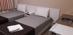 a small room with two beds and a sink at BH EXPO SUITES & KITNETES in Belo Horizonte