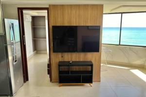 Atlântico Flat في ناتال: غرفة معيشة مع تلفزيون بشاشة مسطحة على جدار