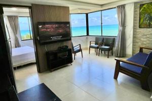 a living room with a television and a room with a view of the ocean at Atlântico Flat in Natal