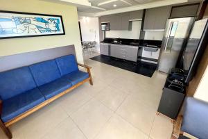 a living room with a blue couch and a kitchen at Atlântico Flat in Natal +24 photos