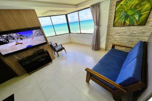 a bedroom with a blue bed and a flat screen tv at Atlântico Flat in Natal
