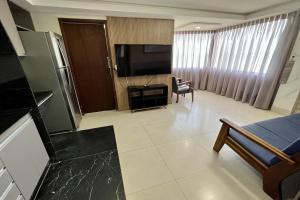een woonkamer met een televisie en een woonkamer met een bank bij Atlântico Flat in Natal