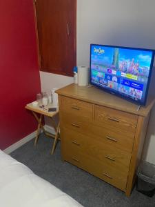 a bedroom with a television on a dresser with a table at Southway Double Room near Derriford in Plymouth