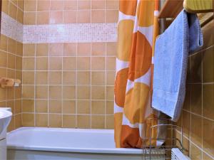 a bathroom with a tub and a shower curtain at Studio cosy avec coin montagne, balcon sud et casier à ski - 4 couchages à Risoul 1850 - FR-1-330-61 in Risoul +7 photos