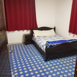 - une chambre avec un lit recouvert de moquette bleue et blanche dans l'établissement Hotel camping amtoudi, à Id AÃ¯ssa