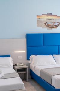 dwa łóżka w pokoju z niebieskimi szafkami w obiekcie Hotel Continental w mieście Tortoreto Lido