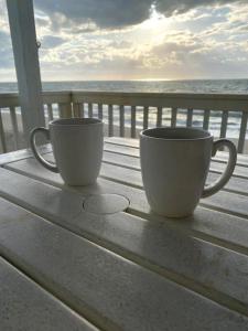 dos tazas de café sentadas en una mesa cerca del océano en Ocean Dunes 1701 Seas The Day, en Kure Beach