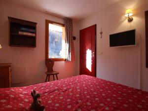 PelvouxにあるAppartement Pelvoux, 2 pièces, 6 personnes - FR-1-330G-83の赤いベッド、窓、テレビが備わるベッドルーム1室が備わります。