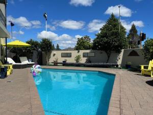 a swimming pool in a yard with a umbrella at Academy Motor Inn in Tauranga