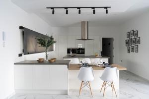 a kitchen with white cabinets and two white stools at Villa Lemar in Urda