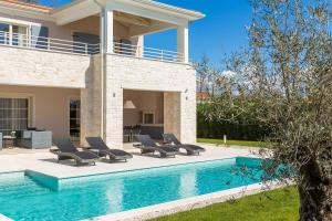 a pool with lounge chairs next to a house at Villa Florence by ILC-Istria Luxury Collection in Brtonigla