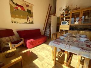 a living room with a table and a red couch at Appartement Vallouise-La Casse, 2 pièces, 5 personnes - FR-1-330G-34 in Le Poët