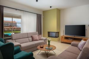 a living room with couches and a flat screen tv at Villa Florence by ILC-Istria Luxury Collection in Brtonigla