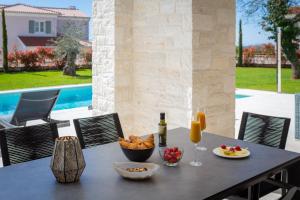 a table with a bowl of fruit and a bottle of wine at Villa Florence by ILC-Istria Luxury Collection in Brtonigla