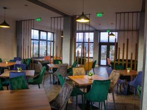 um restaurante com mesas e cadeiras de madeira e janelas em Belvedere Restaurant & Rooms em Topliţa
