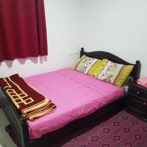 a bedroom with a bed with pink sheets and a dresser at Hotel camping amtoudi in Id AÃ¯ssa