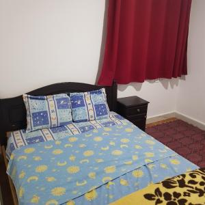 a bed with a blue comforter and pillows on it at Hotel camping amtoudi in Id AÃ¯ssa