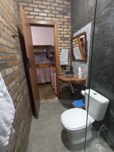 a bathroom with a toilet and a wooden door at Canto Ybykuara - Natural Guest House in Ibicoara