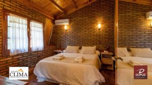 a bedroom with two beds and a brick wall at DOMUS AUDITORIUM in Villa Carlos Paz