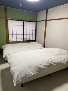 two twin beds in a room with two windows at guest house goose - Vacation STAY 23621v in Hirosaki