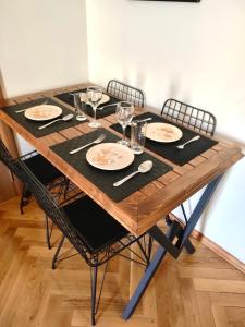 einen Holztisch mit Stühlen, Tellern und Weingläsern in der Unterkunft Apartman Filip in Podgorica