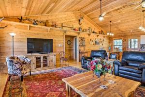a living room with furniture and a tv in a log cabin at Cozy New Braunfels Family Cabin with Porch and Views! in New Braunfels