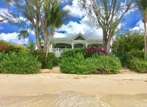 ein Haus am Strand mit Bäumen und Blumen in der Unterkunft La Paloma by Blue Sky Luxury in Saint James