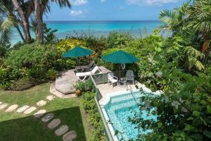 ein Swimmingpool mit Stühlen und Sonnenschirmen neben dem Meer in der Unterkunft La Paloma by Blue Sky Luxury in Saint James