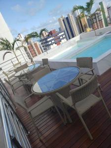 una mesa y sillas en un balcón junto a la piscina en Manaíra Apart Hotel 1505, en João Pessoa