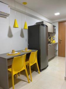 eine Küche mit gelben Stühlen, einem Tisch und einem Kühlschrank in der Unterkunft Manaíra Apart Hotel 1505 in João Pessoa