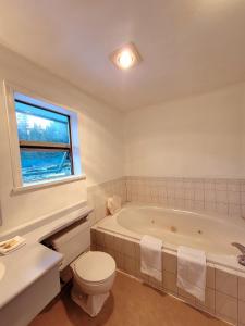 La salle de bains est pourvue d'une baignoire, de toilettes et d'une fenêtre. dans l'établissement Ridgeview Motor Inn, à Gold River